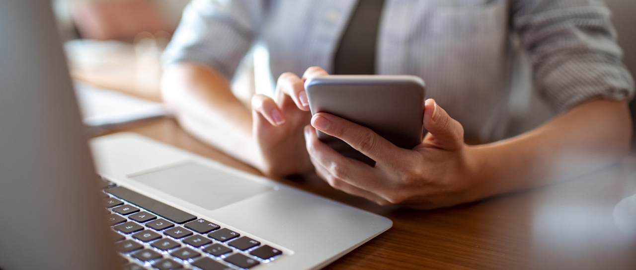 Someone using an aluminium smartphone and laptop