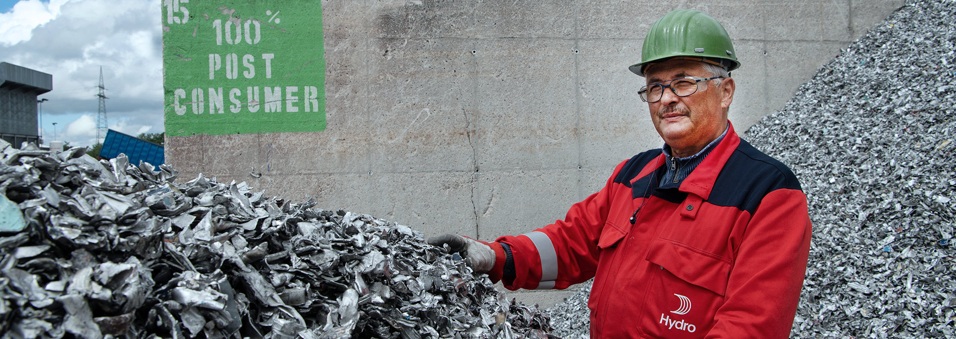 a man wearing a hard hat and standing next to a pile of garbage